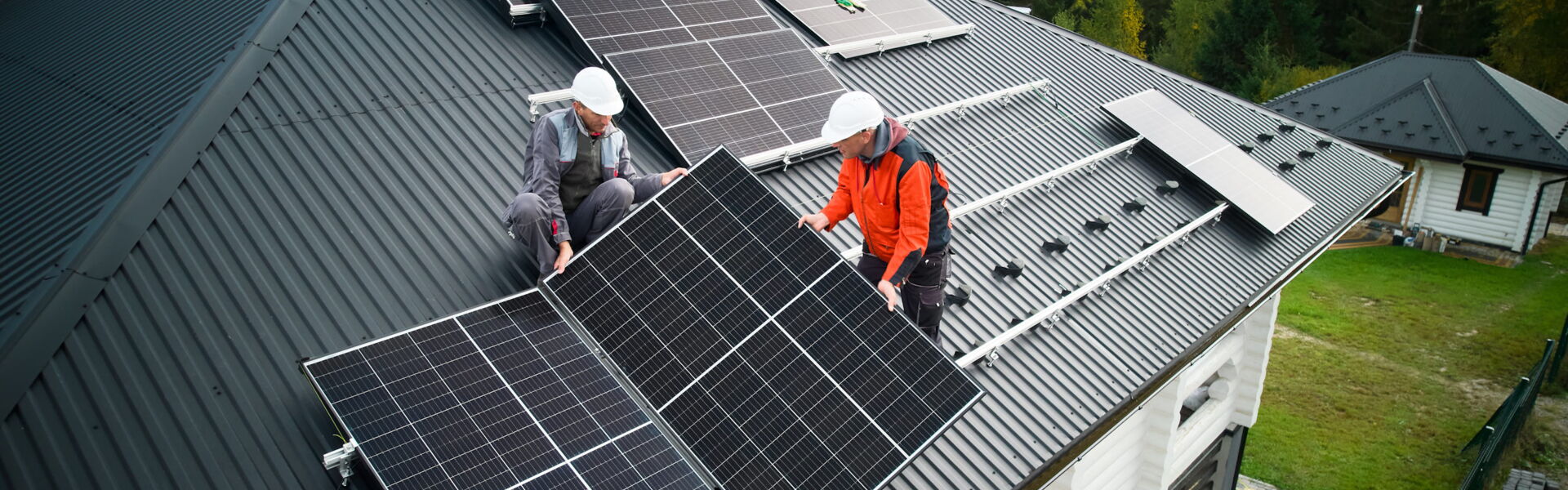 Solarteure installieren eine Solaranlage auf dem Dach eines Einfamilienhauses.